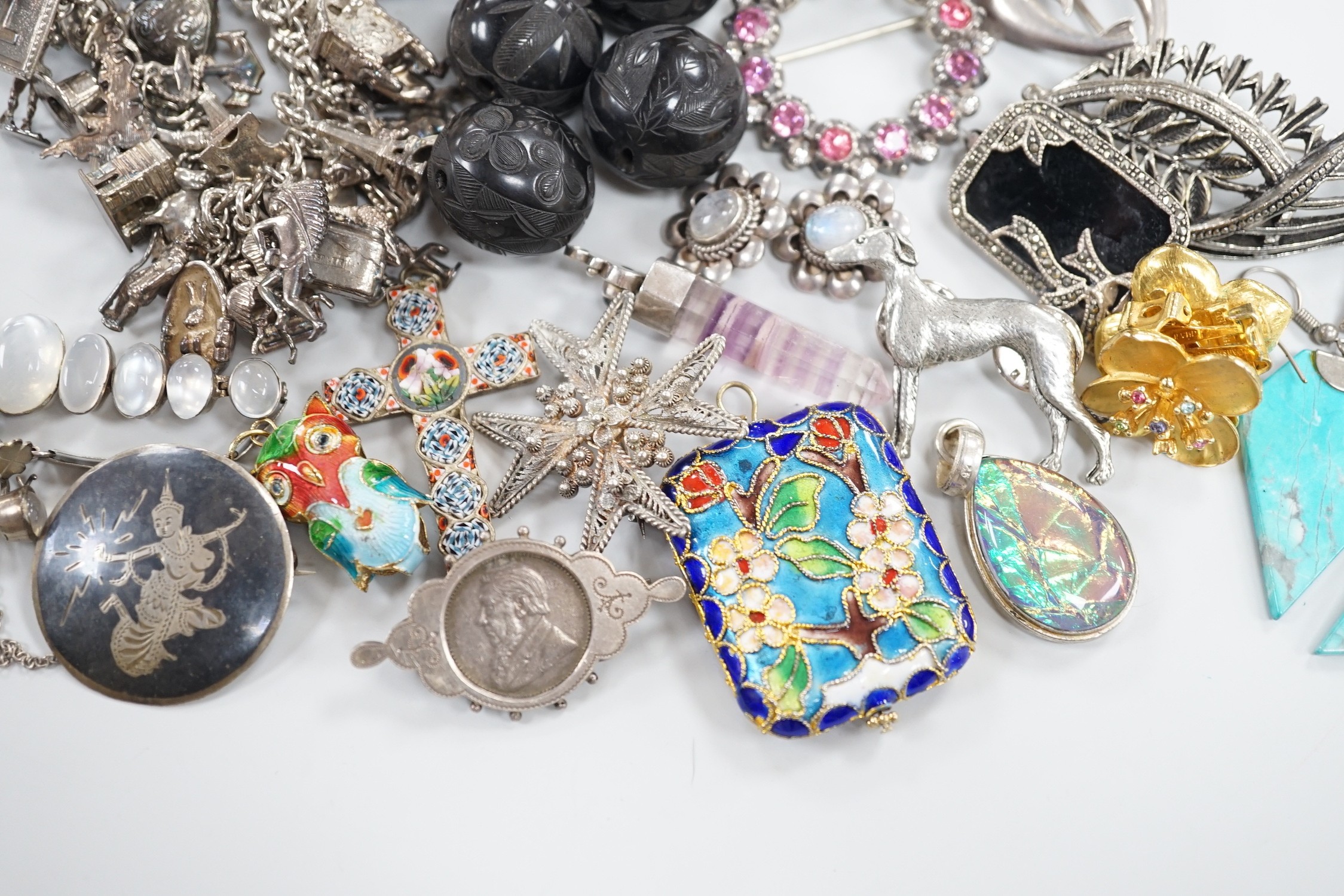 A silver charm bracelet hung with fifty assorted charms and a group of assorted jewellery including enamelled locket, Victorian agate fob seal carved with a bird, scarab pendant, coloured paste set brooch, 925 triple dol